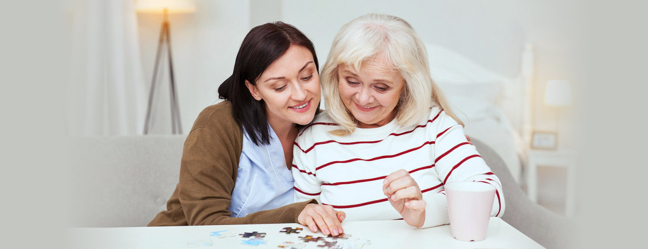 caregiver and senior woman playing puzzle