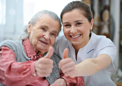 caregiver and senior woman doing thumbs up
